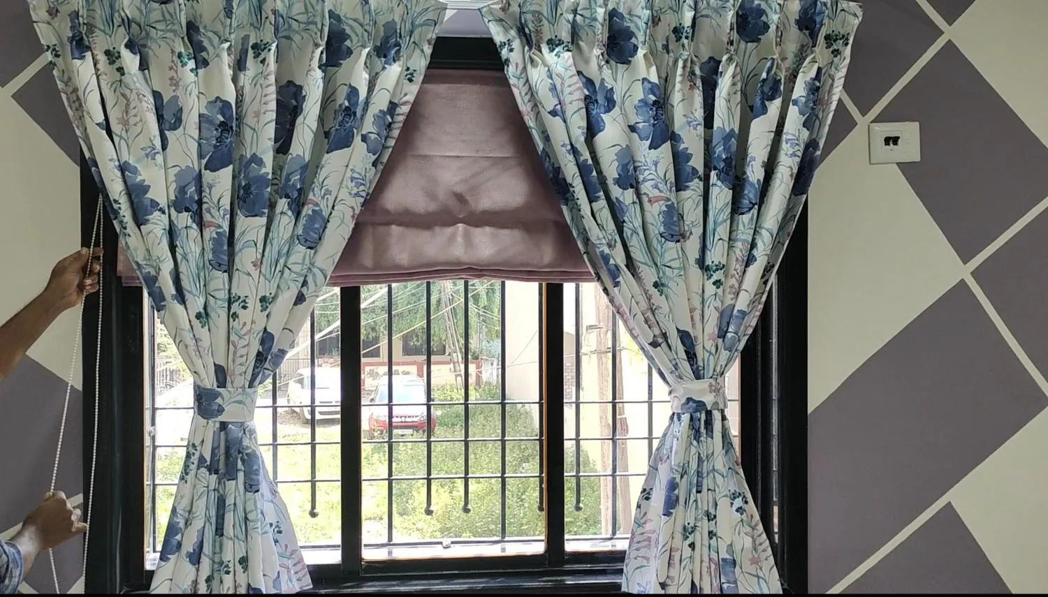 Floral pinch-pleat curtains with tie-backs over a mauve Roman blind, installed by New Decent Furnishing